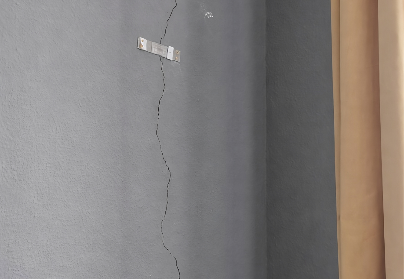 Fissure verticale sur un mur intérieur proche d’un angle avec témoins de fissuration permettant de suivre l’évolution des mouvements