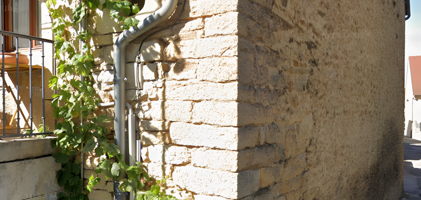 Angle de bâtiment en pierre avec chaîne d’angle visible composée de blocs appareillés formant un harpage assurant la liaison entre deux murs